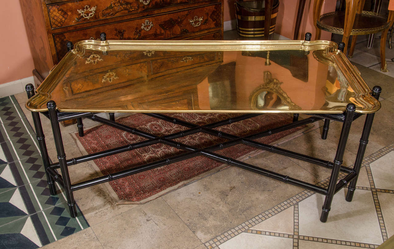 A Mid-Century German brass molded edge tray with outset corners, mounted as a coffee table on a black painted bamboo turned stand.