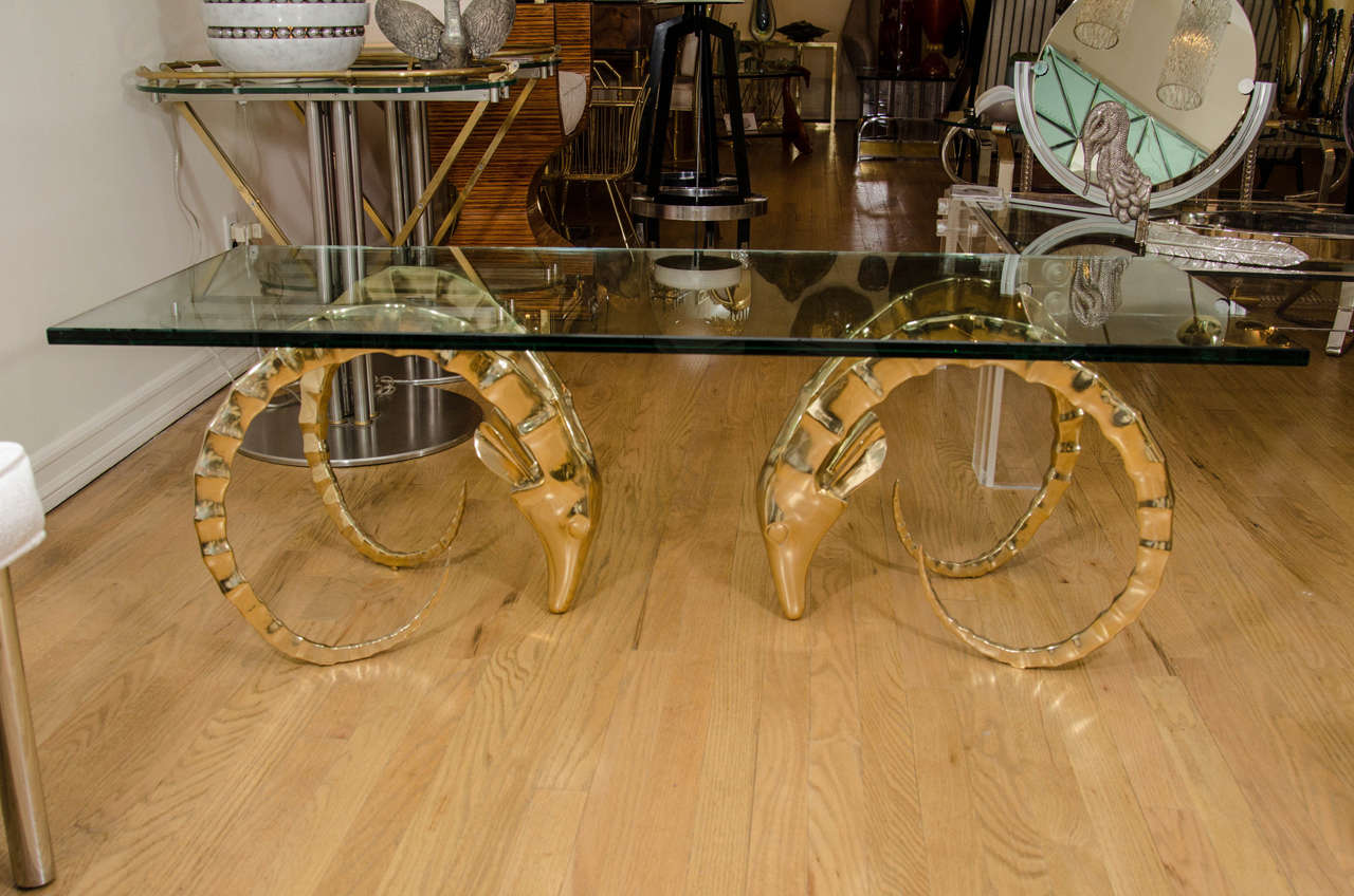 Large rectangular brass ram's head coffee table with glass top.
