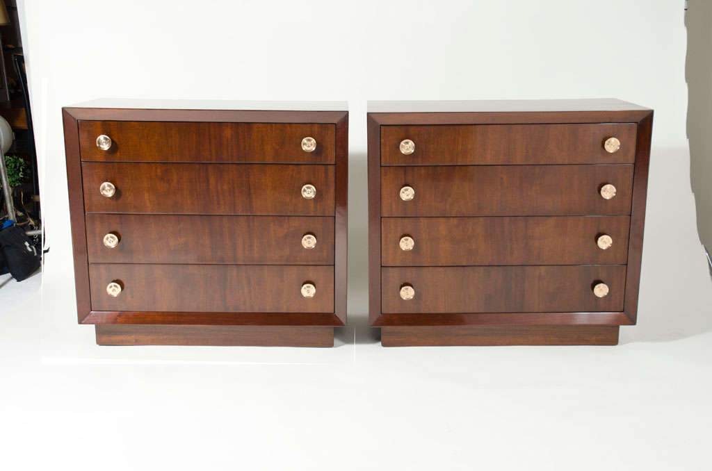 A fine pair of commodes comprising four drawers with dimpled round brass disc pulls and a case with a chamfer edge the whole resting on a plinth base all in a beautifully figured mahogany. By Modern Age. U.S.A., circa 1950. [DUF0249]