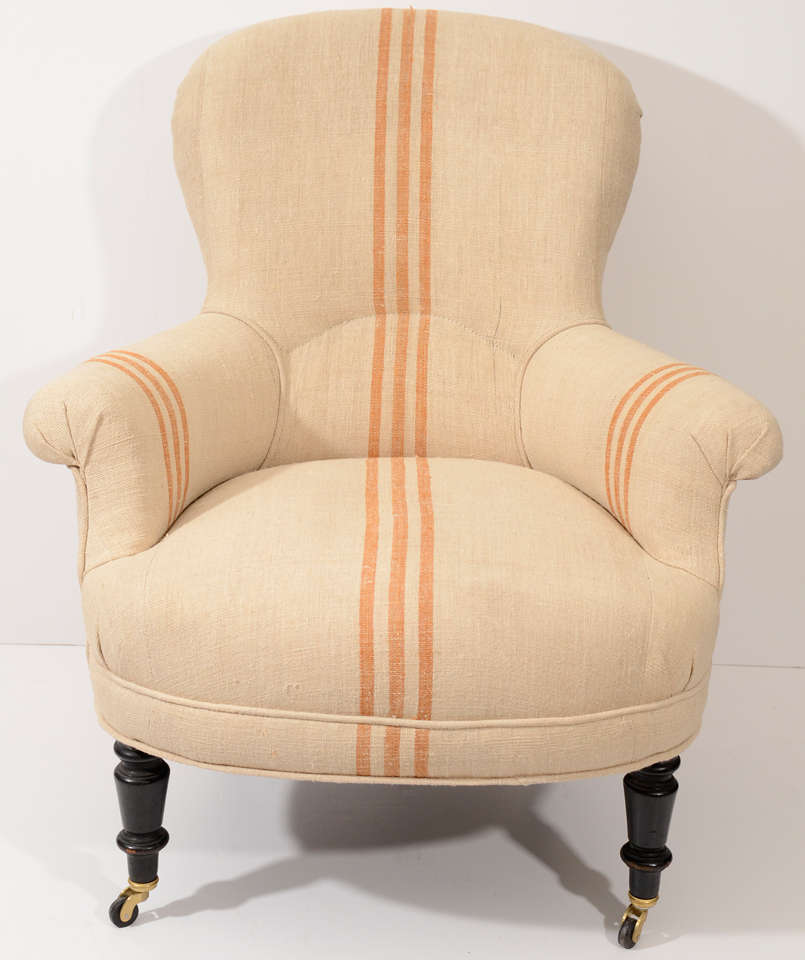 Upholstered in homespun linen with a butterscotch colored stripe on hand turned legs with casters.