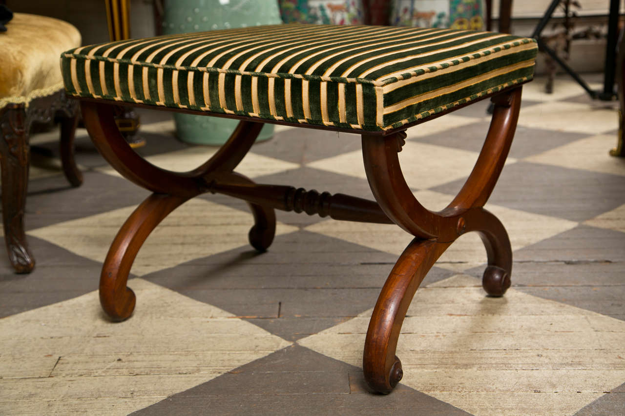 an early 19th century foot stool in curule form in the Duncan Phyfe, NYC manner, upholstered foot rest. central stretcher with turnings. bulls eye roundels at the bottom of the legs. this could be also used as a sitting stool.