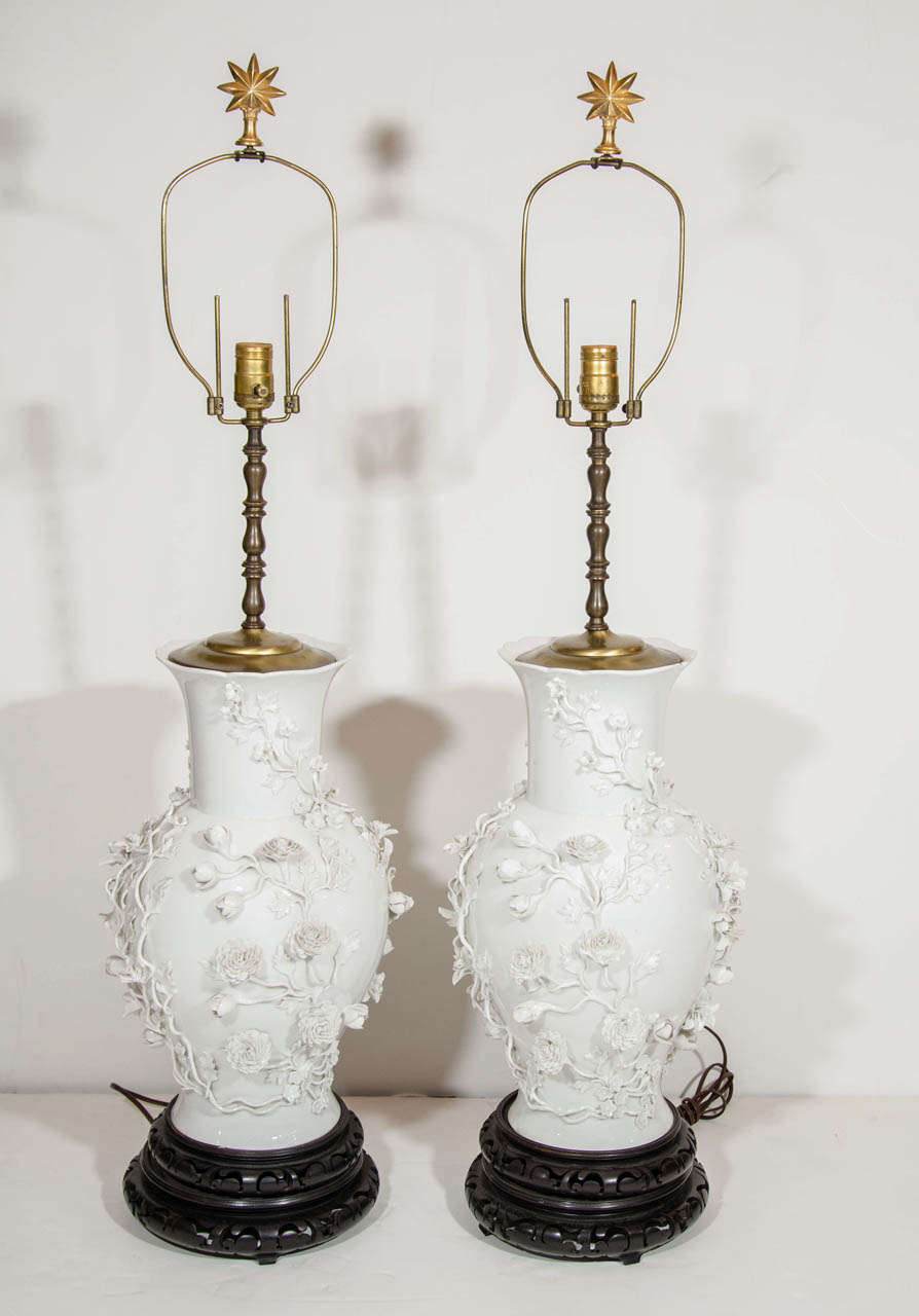 A pair of Exquisite & highly important large Antique Chinoiserie style Chinese Blanc De Chine Porcelain Lamps of superb craftsmanship embellished with three dimensional hand made raised porcelain flowers, leaves & branches further adorned on carved