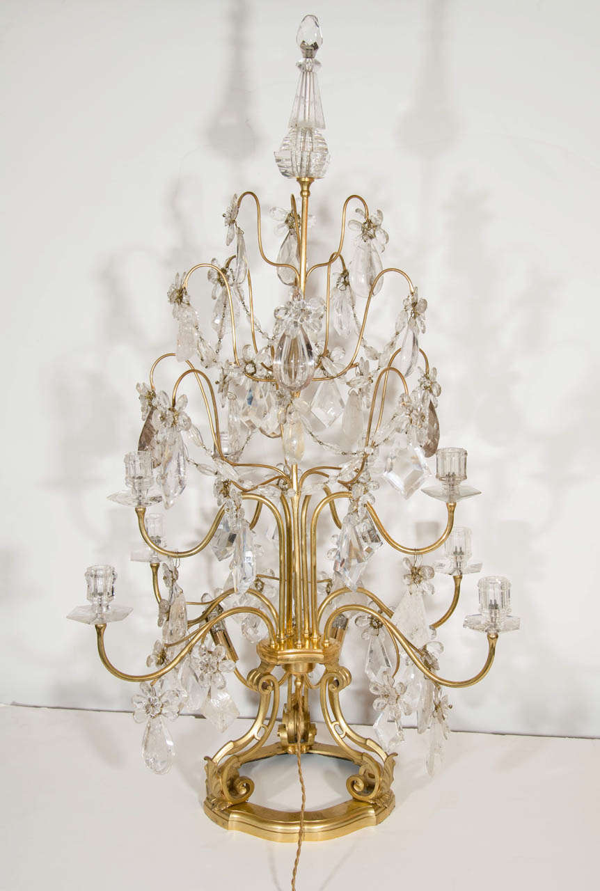 Set of four large French Louis XVI style multi light gilt bronze and cut rock crystal candelabra lamps embellished with cut rock crystal prisms, chains, flowers and finally decorated with a large rock crystal finial.