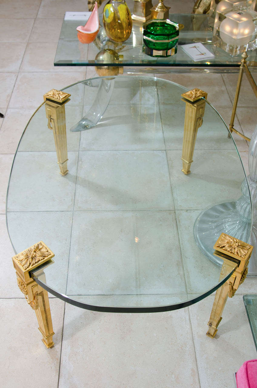 Oval glass top cocktail table with gilt bronze neoclassical supports by P.E. Guerin.