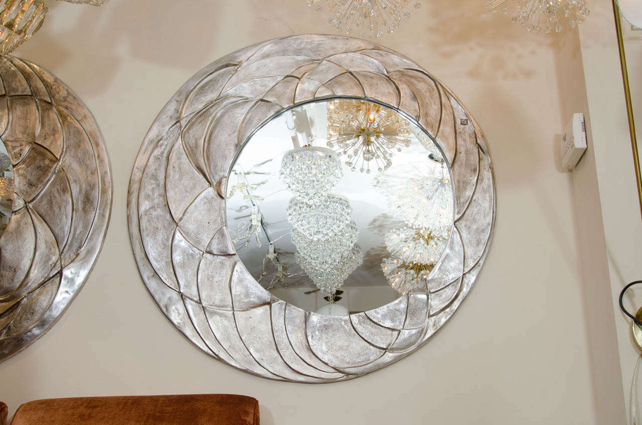 Asymmetrical ovoid mirror with a textured relief, aluminum surround.