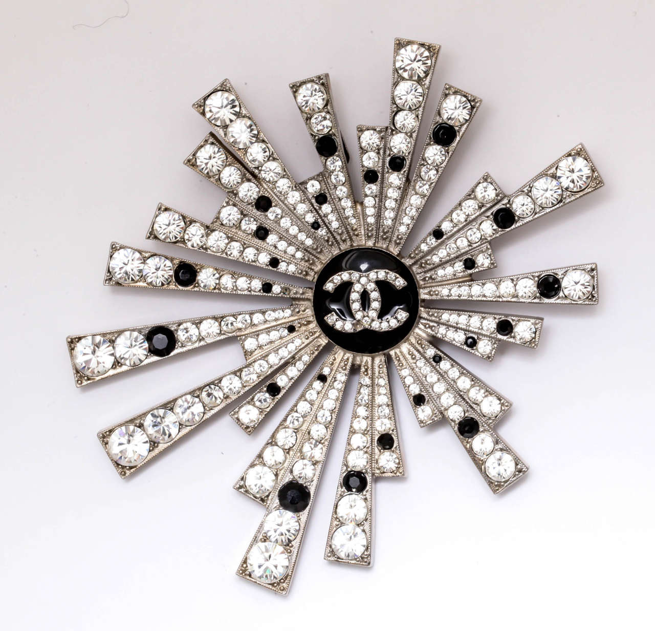 A rare Chanel brooch that can be worn as a pendant with paste stones surrounding an enamel logo. Marked on the back with the Chanel logo from Autumn 05.