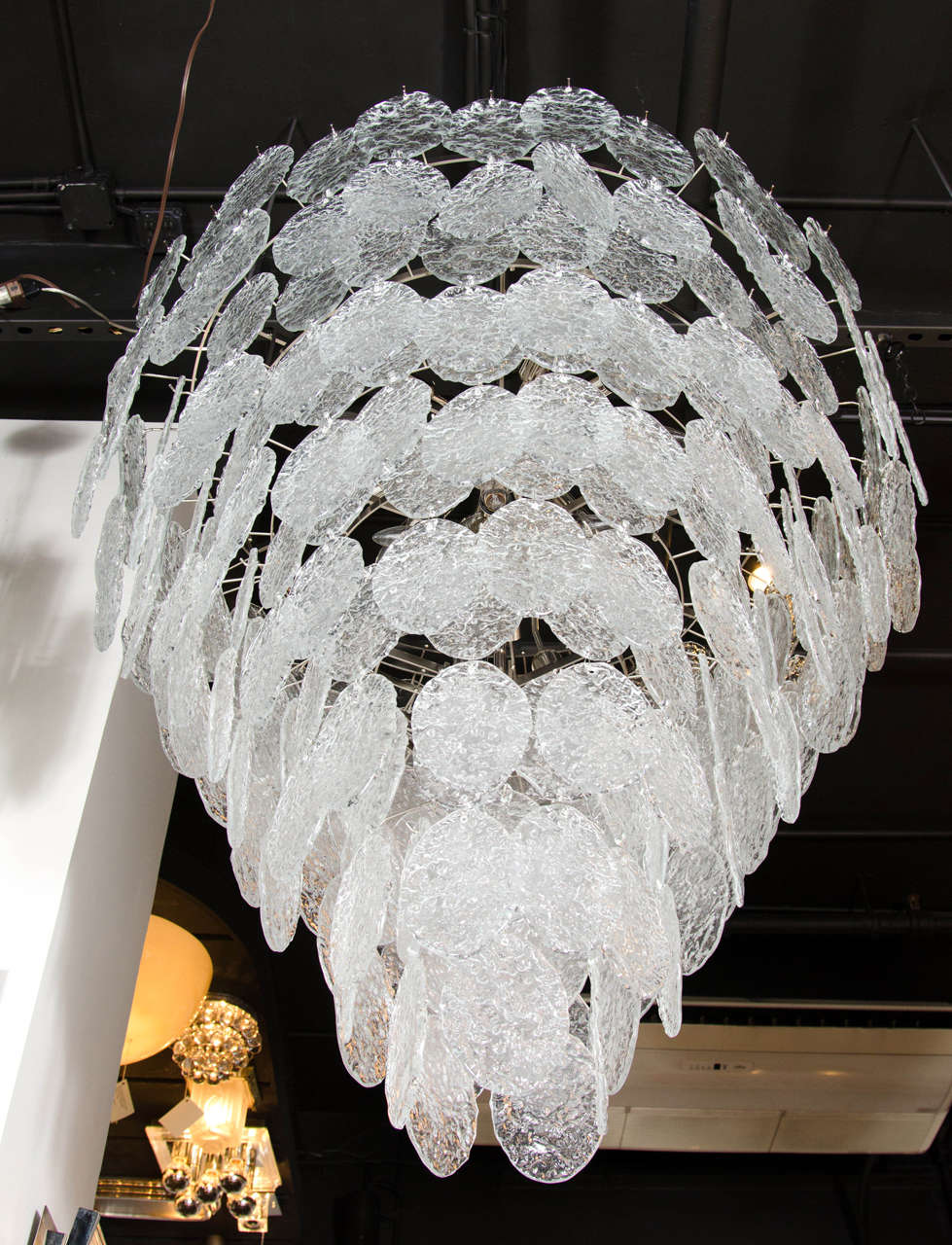 This sophisticated chandelier was handblown in Murano, Italy- the island off the coast of Venice renowned for centuries for its superlative glass production. It consists of multi handblown Murano glass disks in eight tiers in frosted and clear