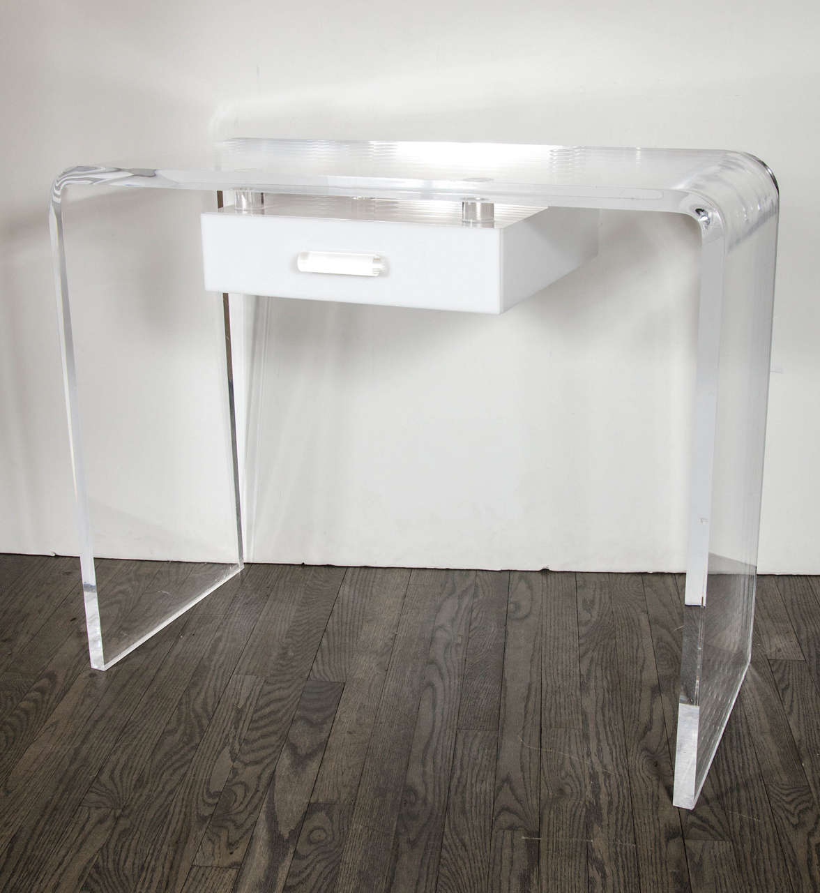 This vanity/desk features a waterfall design in clear lucite with a pull out drawer in white lucite with a clear lucite knob.The drawer appears to have a floating effect making this a special modernist piece.Would be great as a vanity or desk.