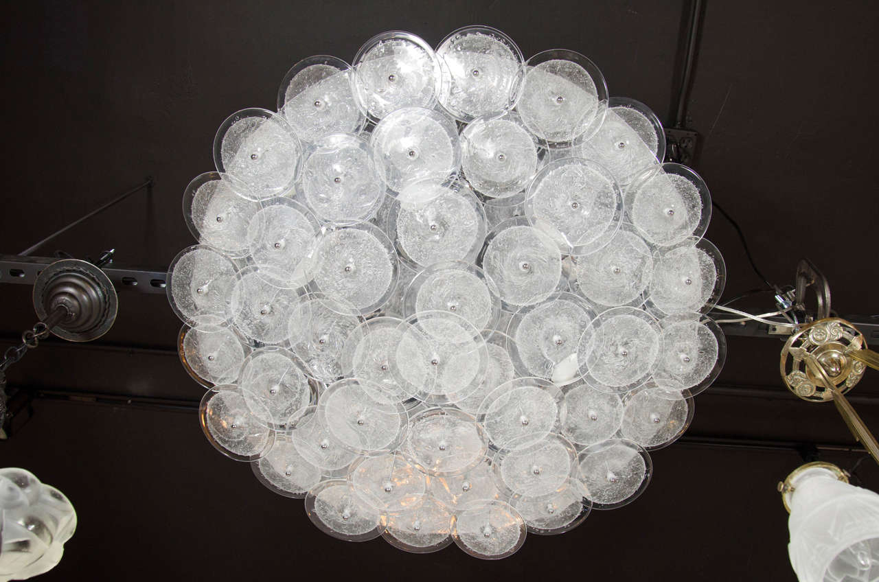 This stunning Modernist chandelier was hand fabricated in Murano, Italy- the island off the coast of Venice renowned for centuries for its superlative glass production. It features an abundance of handblown Murano discs with translucent perimeters