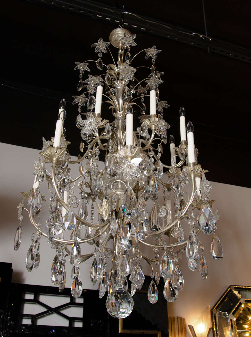 This glamorous Hollywood Regency style chandelier features an abundance of fine cut crystal pendants- resembling cut and beveled diamonds- hanging from silvered bronze fittings. This exquisite chandelier features a stylized canopy with beaded