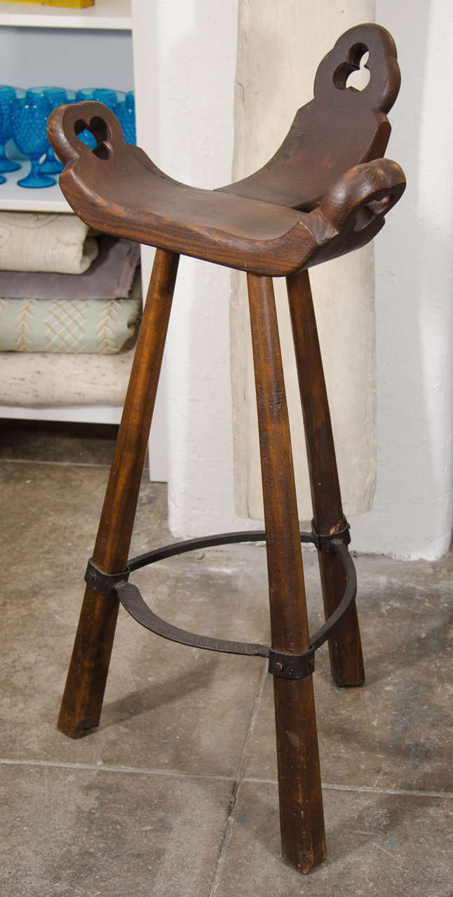 Pair of tripod base stools with iron footrest. Original condition with some natural wear that enhances the beauty of these pieces.