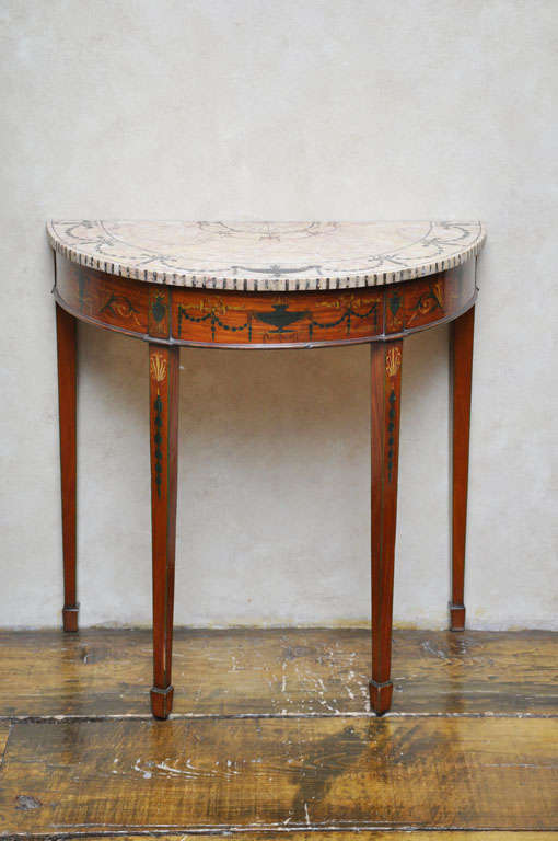 Rare pare of Edwardian period Sheraton revival demilune shaped  satin wood and inlaid marble top console tables. Demilune shaped intricately inlaid pietra dura marble top surface with Neoclassical inspired green covered urns and garlands makes these