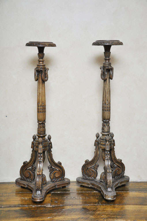 Pair of Italian Louis XVI style floor-standing carved torchiere pedestals, the fluted column shaft draped with carved garland swag supported on intricately carved s-scrolled tripod base surmounted by three acorn finials, the pedestal resting on a