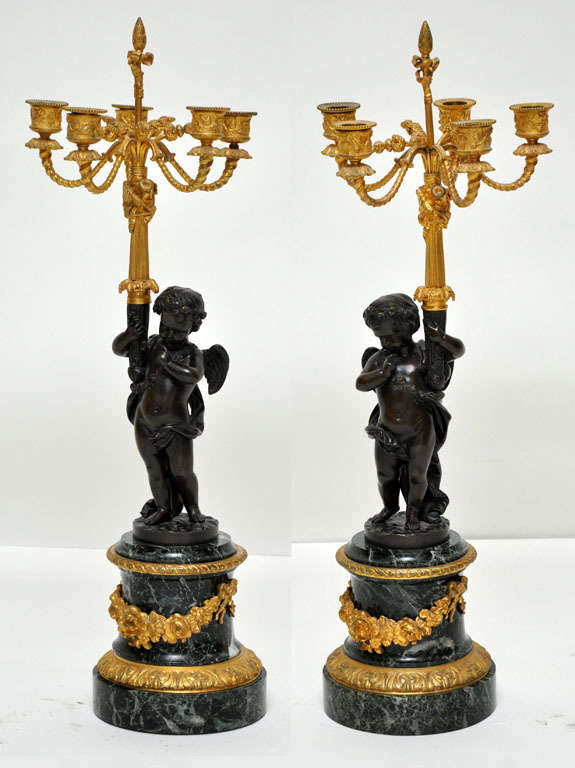 Important pair of Neoclassical Louis XV style dark patinated and gilded bronze figural putti candelabras. The patinated bronze shaft depicting a winged putti or cherub with a rose garland draped across his shoulder, on the back of patinated bronze