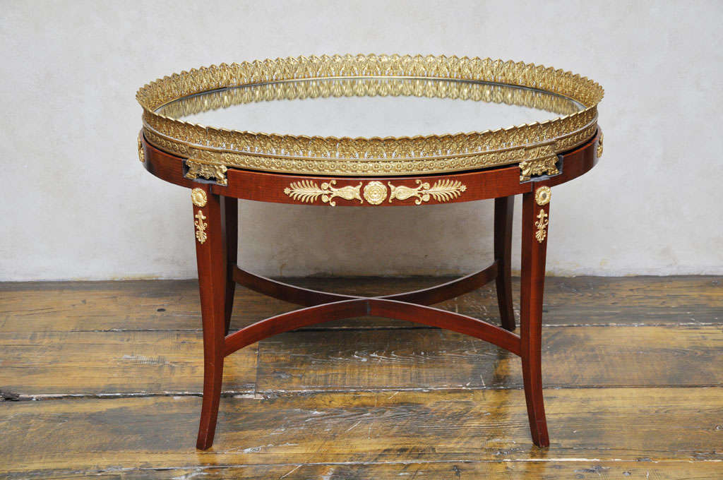 French Empire gilded bronze and mahogany plateau cocktail table, gilded bronze plateau with intricately pierced gilded bronze gallery gilded gallery surrounding a mirrored top surface, supported on a mahogany base with shapely legs adorned with