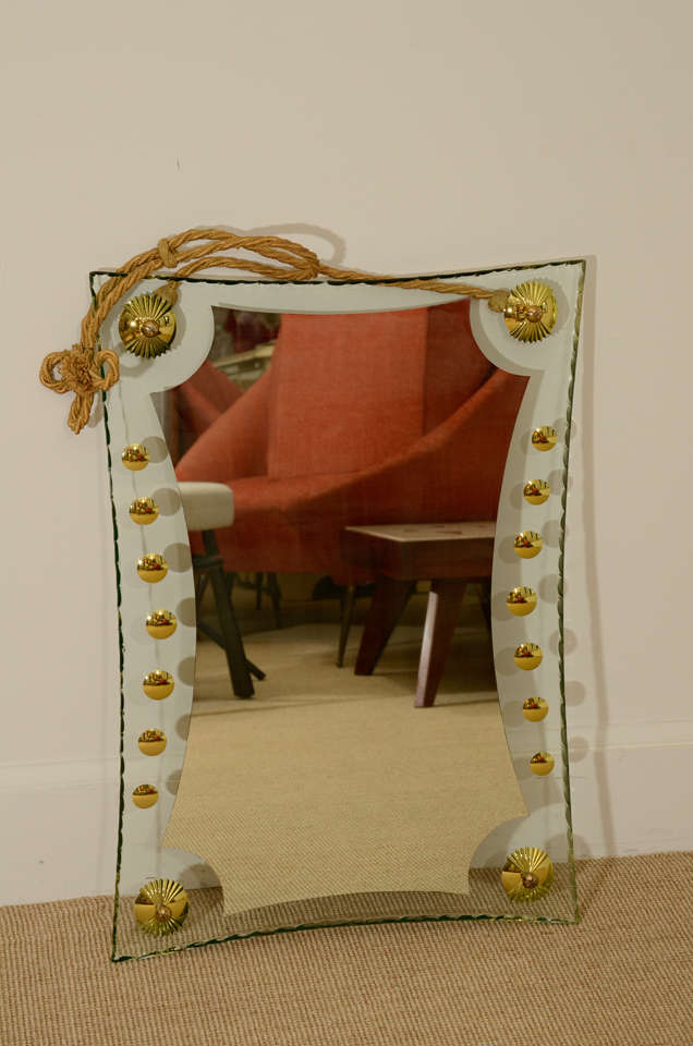 The clear glass edge with a repeated scallop cut band and circular cuts filed with gilt, the corners applied with gilt metal circular motifs and a rope at the top.