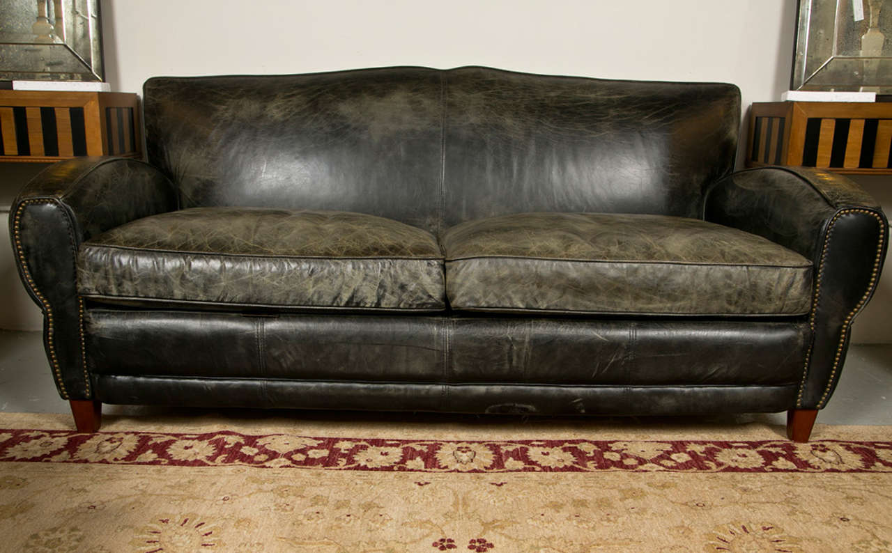A fine quality black leather sofa, The underbody covered in zipped burlap. Formally of Domain Leather in Long Island NY. This nice Art Deco Influanced sofa having mahogany tapering legs which lead to tapering side arms with bullet tacts having