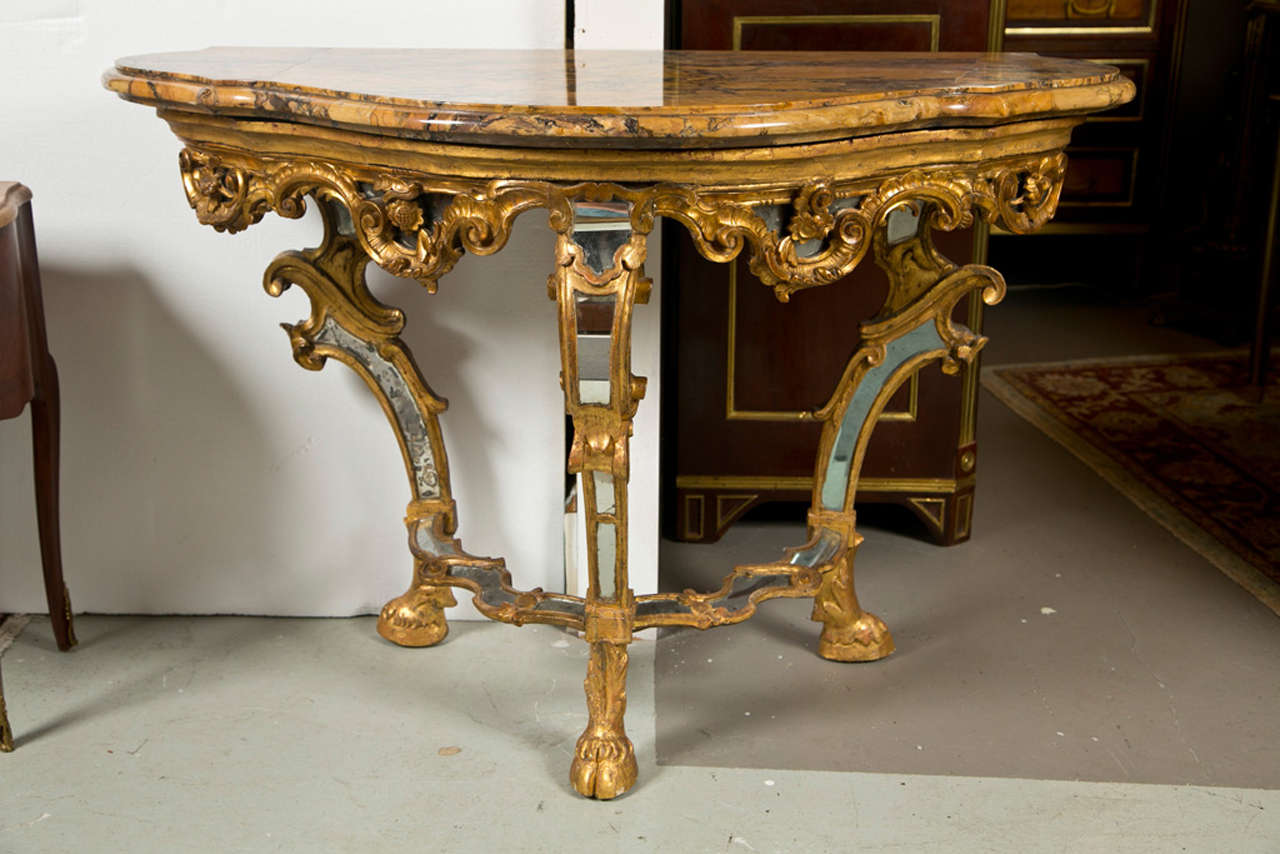 Finest Italian Gilt-wood and Mirror-Insert Console Table. Rome. Second Quarter 18th Century. Serpentine Siena marble top above foliate scrolling frieze on scrolling legs joined by carved under-carriage with mirrored panels some mirrored panels have