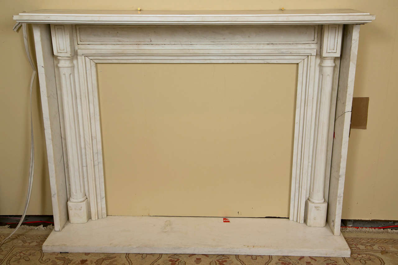This a a finely crafted Carrera Marble Fireplace Surround. The side walls framing the interior column form side. With a marble floor base. Freestanding. Inside dimensions: 34H 39.5W