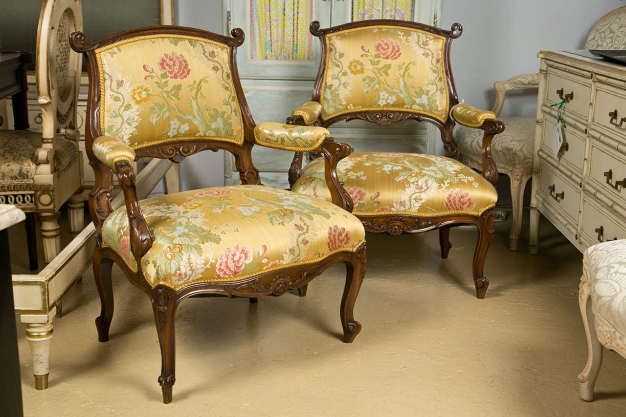 Pair of intriging French Rococo style walnut armchairs, padded back, armrest, and seat upholstered in silk, raised on cabriole legs. 