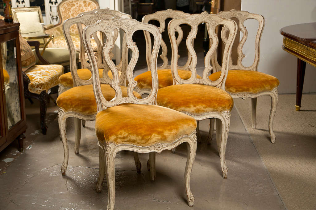 Set of 12 attractive French Louis XV style side chairs, circa 1940s, each has white painted and distressed frame, the padded seat upholstered in yellow velvet, raised on cabriole legs. By Maison Jansen. 