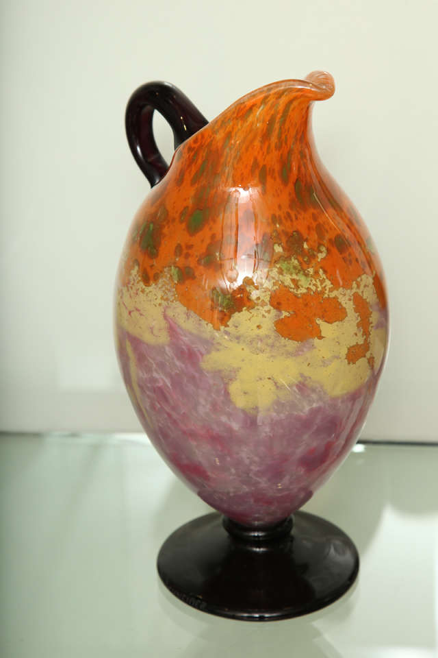Charles Schneider, French Art Deco glass ewer.
Pink and yellow powdered glass with spots in orange, pink, and green powder inclusions, applied violet handle, circa 1922.
Engraved: Schneider.
Measure: 11-1/2 inches high (29.2 cm).
 