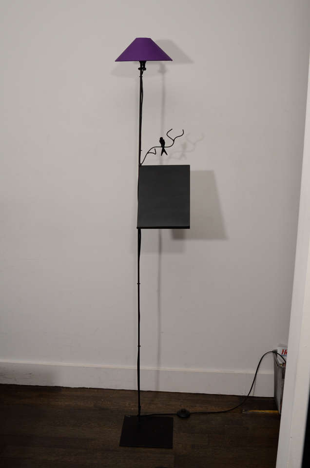 Handmade floor lamp with bronzed steel finish accented by a sculptural bird perched atop a branch and sheet music shelf platform. Lampshades available in purple, white or green.