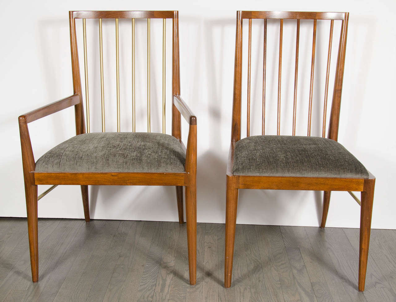 Set of eight Mid-Century style dining chairs in Walnut.  Inspired by Danish design, there are six side chairs that feature a slanted spindle back and solid brass leg supports.  The two armchairs have a solid brass spindles and brass leg supports. 