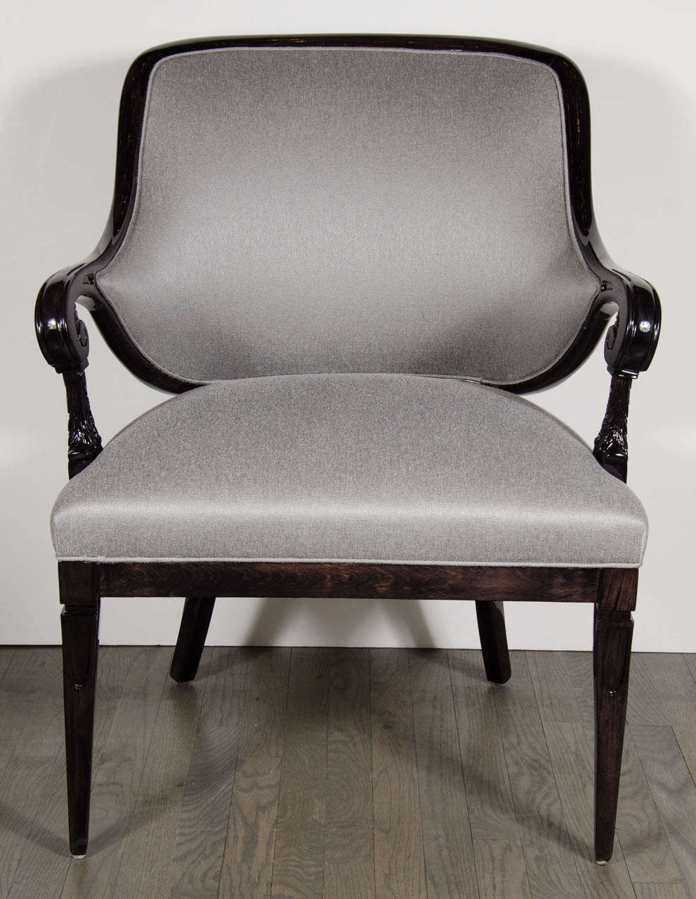 This glamourous pair of chairs  feature a scrolled arm design with stylized hand carved plume detailing . They are made of ebonized walnut and newly upholstered in platinum sharkskin. These are in restored mint condition.