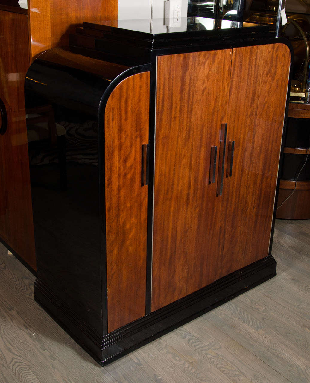 This stunning bar cabinet features exotic mahogany book-matched doors,streamlined Nickel pulls and black lacquer.The two larger doors open to reveal a black lacquer interior fitted with two shelves for great storage of barware and four smaller