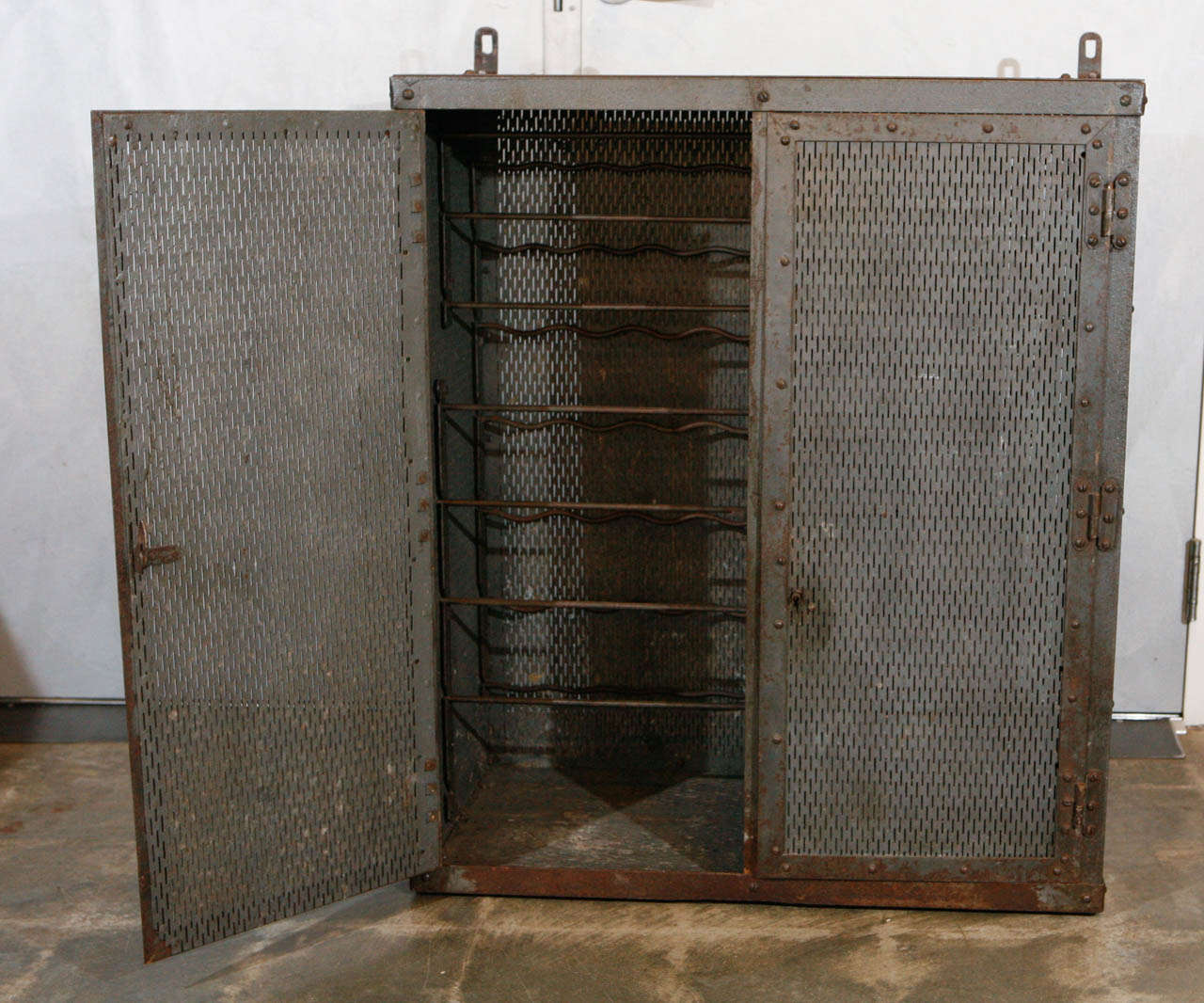 This handsome french industrial metal cabinet from the 1930's was converted into a wine safe at some point in it's history. Note the elegant weave of the wire mesh walls and slender shape of the hinges and a beautiful patina throughout.  The piece