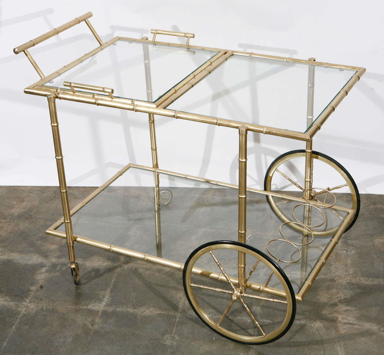 This Italian, brass faux bamboo Bar Cart with glass shelves from the 1940's is a great find with with a removable top tray and four rubber lined wheels. This piece has some great details: the angled bottle rack and miniature bamboo detailing on the