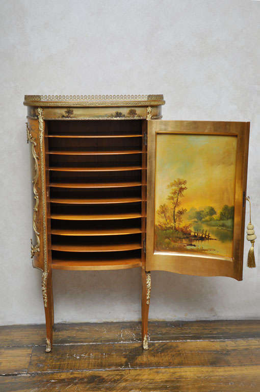 French Vernis Martin music cabinet.  The interior is fitted out with nine shelves.  The inside door panel depicts a beautiful landscape.  The outside door panel has a scene with a nymphe and three putties that is surronded with a gilded bronze