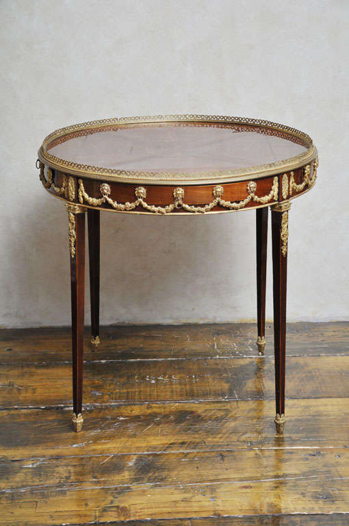 18th Century Sheraton side table with circular veneered sunburst design surface with a pierced bronze gallery.  A hand chaised gilded bronze mounted frieze adorned with lions heads supporting a garland of swags, which contains a shallow drawer on