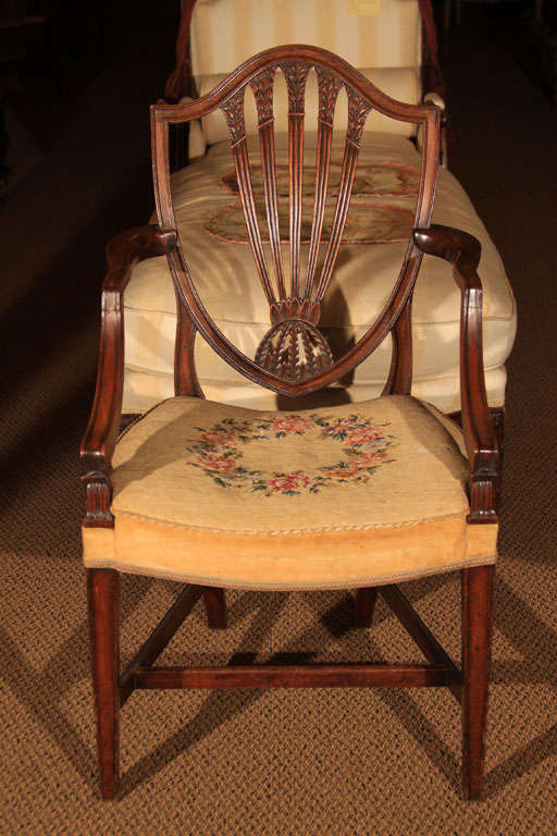 English George III Mahogany Shield Back Arm Chair

This lovely chair features the traditional shield back with reverse arm and tapered legs. The stretcher system in the base is original as is the gross point tapestry seat with bow front and