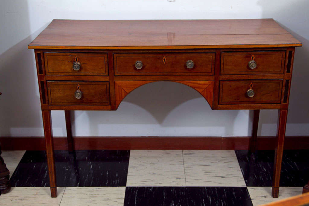 This antique mahogany dressing table has acquired a rich patina over the years as the mahogany has warmed to a rich honey brown. The top edge is inlaid with satinwood and ebony stringing elements of woods that are repeated throughout the case and