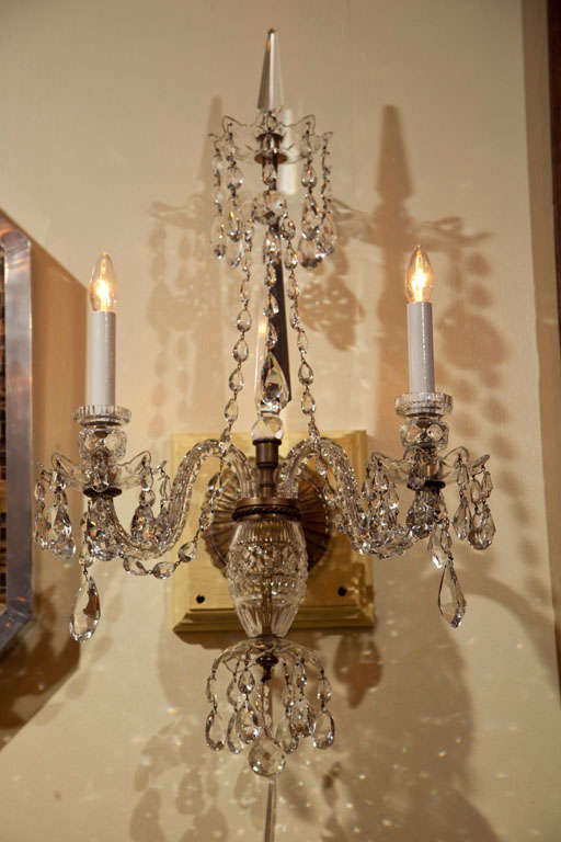 Pair of Irish cut crystal sconces with two lights, crystal drops and swags and a central crystal spire.