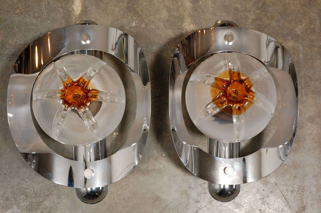 An appealing pair of Italian wall sconces, circa 1960's, by Mazzega. Each sconce has a colorful art glass shade in the form of a globe with amber coloring. The sconces have elegant sculptural chrome elements encircling the murano glass globes.  