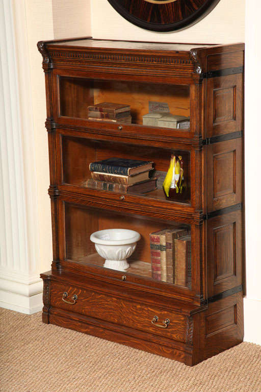 Old Oak Globe Wernicke Stacking Bookcases(Three Graduating Bookcases) resting on lower Drawer section.  Features include Panel Ends, Fluted Columns, Hand Carved Leaves and Bevel Glass Lifting Doors.  Circa 1900.
