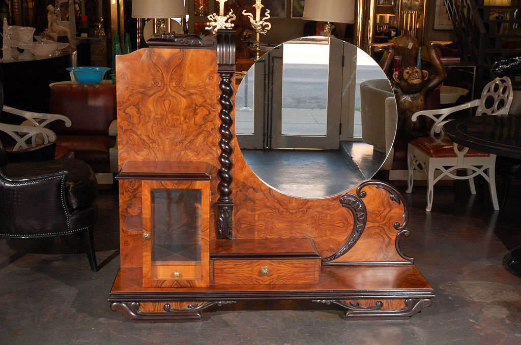 A unique French Art Deco Vanity. Piece has a multi level shelves, a cabinet and two drawers. Hold a free floating circular mirror.