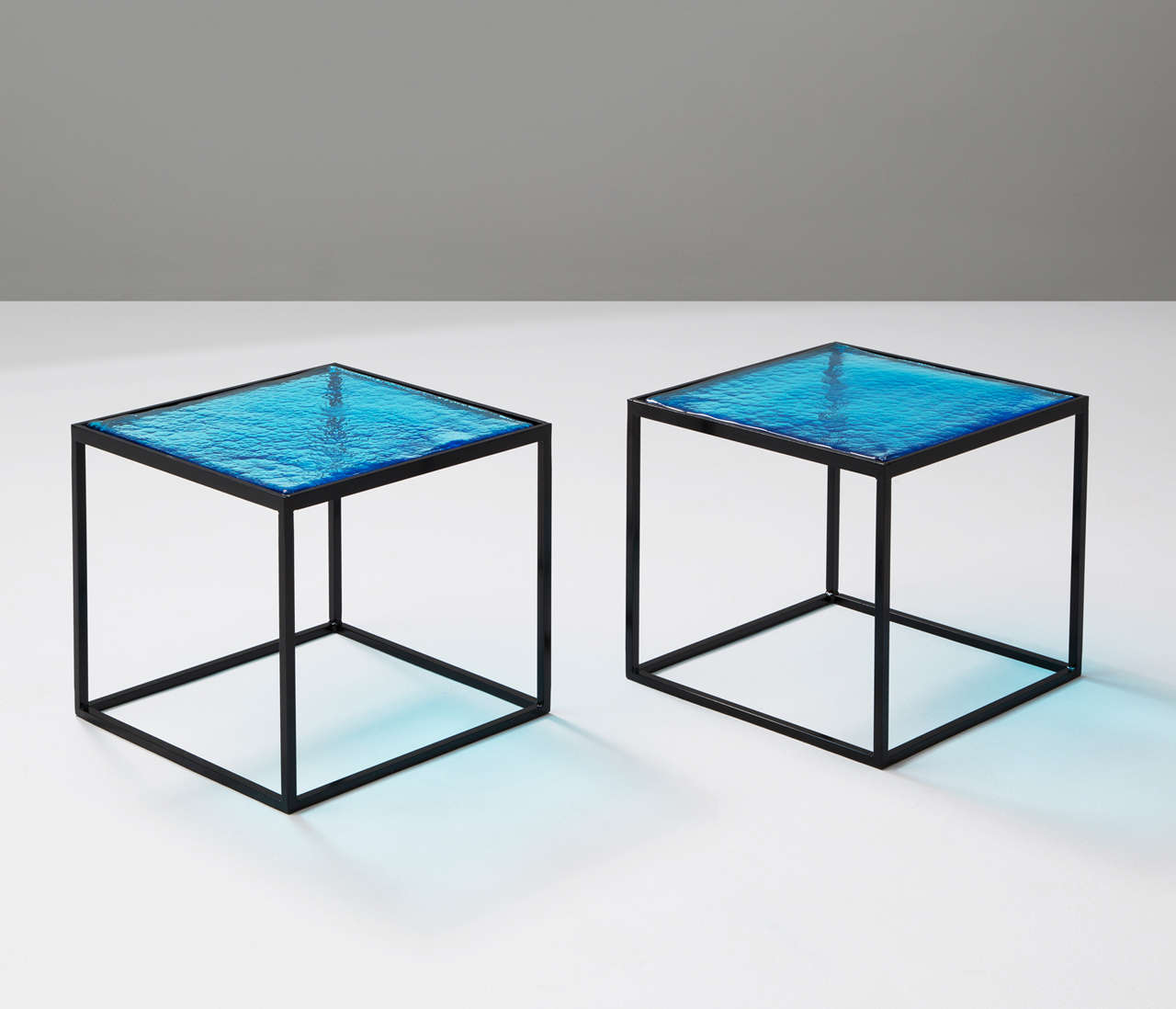 This Italian glass was made by melting raw materials under high temperatures adding colored glass which gives this side tables their unique pattern and airy elegance. Combined with a solid black-coated metal 