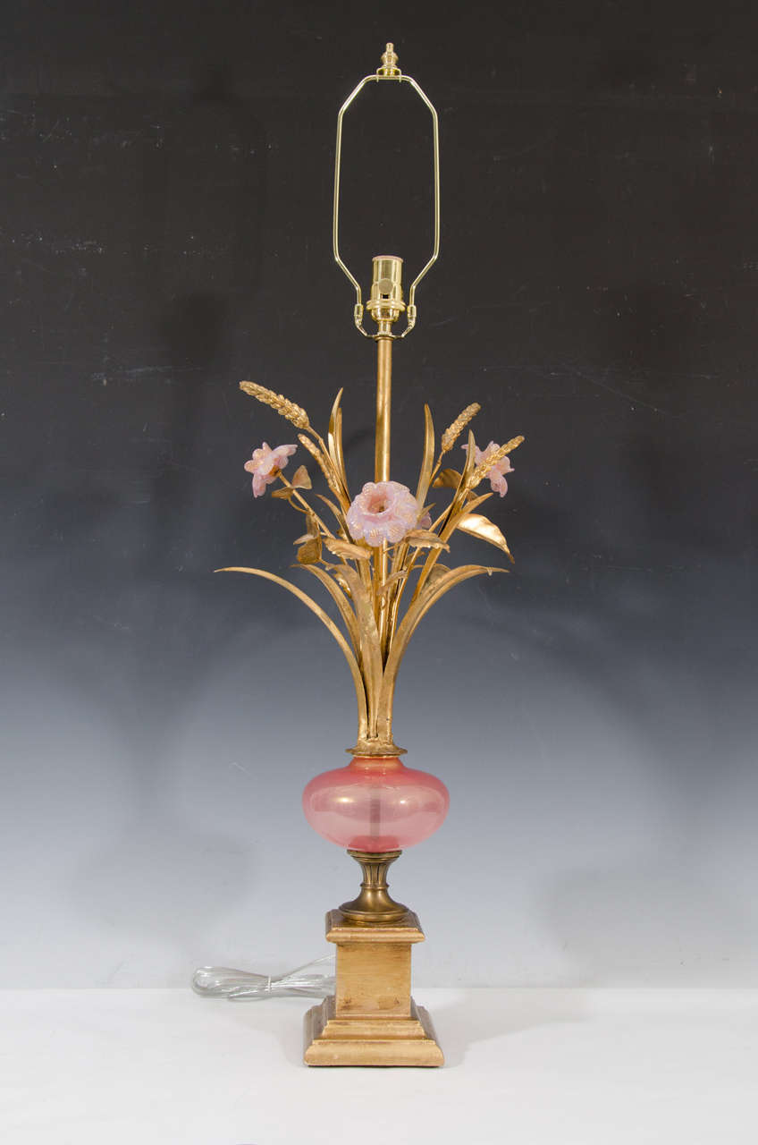 A vintage pair of Murano table lamps with pink glass bodies, tole leaves in gold leaf finish and hand blown pink glass flowers. The wood base is gold leaf.