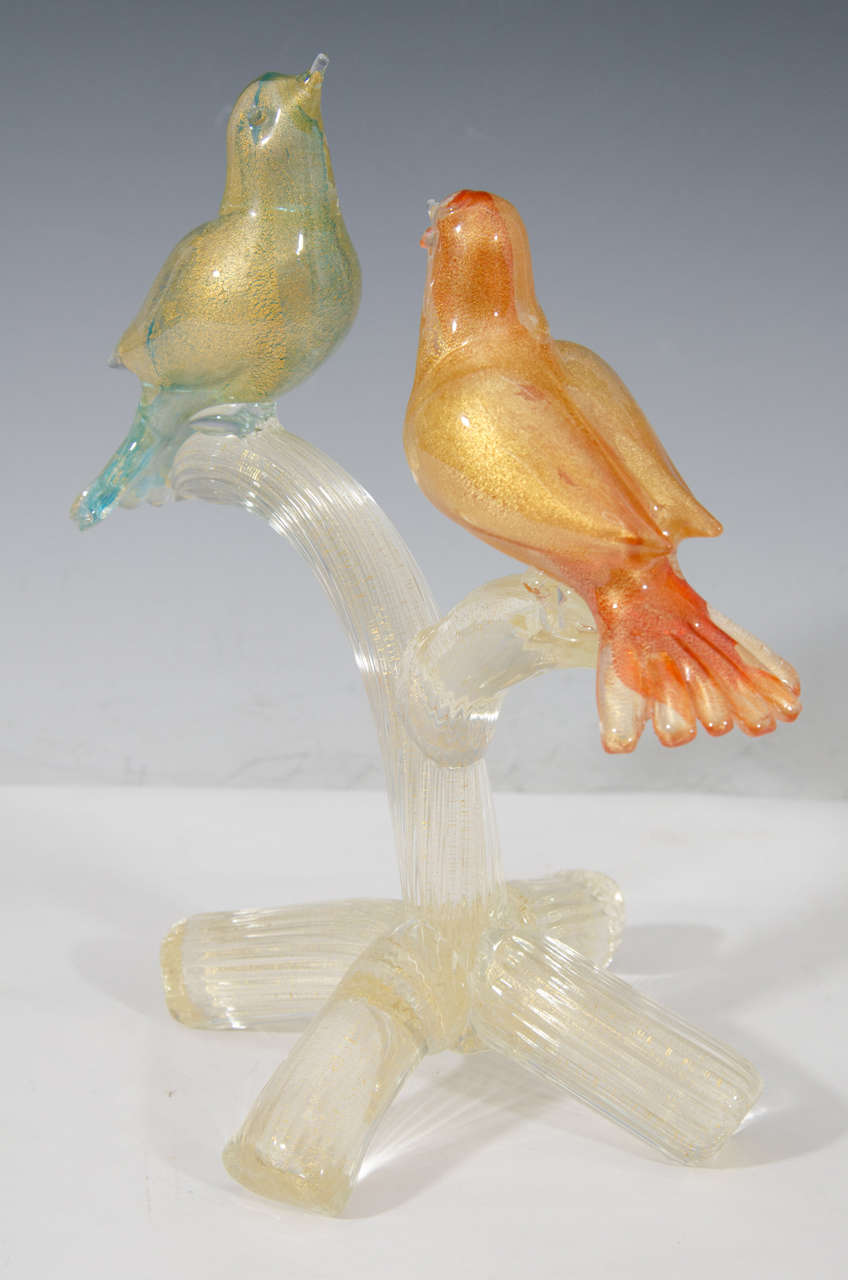 A vintage Formia Murano glass sculpture of a blue and orange gold infused cased birds on a tree branch.