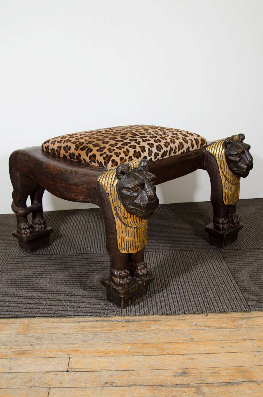 An Egyptian Revival style gilt wood, heavily carved, and highly decorative, sculptural lion bench, or stool with leopard print upholstery.

Good vintage condition with age appropriate wear.  Some scuffs to the wood.