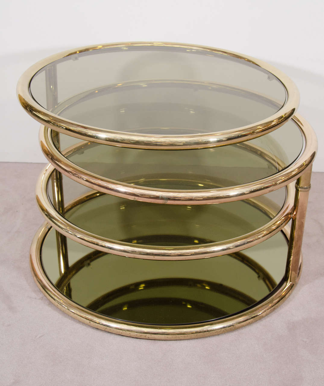 A vintage Milo Baughman style three-tier brass and smoked glass coffee table or cocktail table. The top two tiers of this versatile table pivot to expand to a width of 73.5 inches. It can function as a side table when closed or a coffee table when