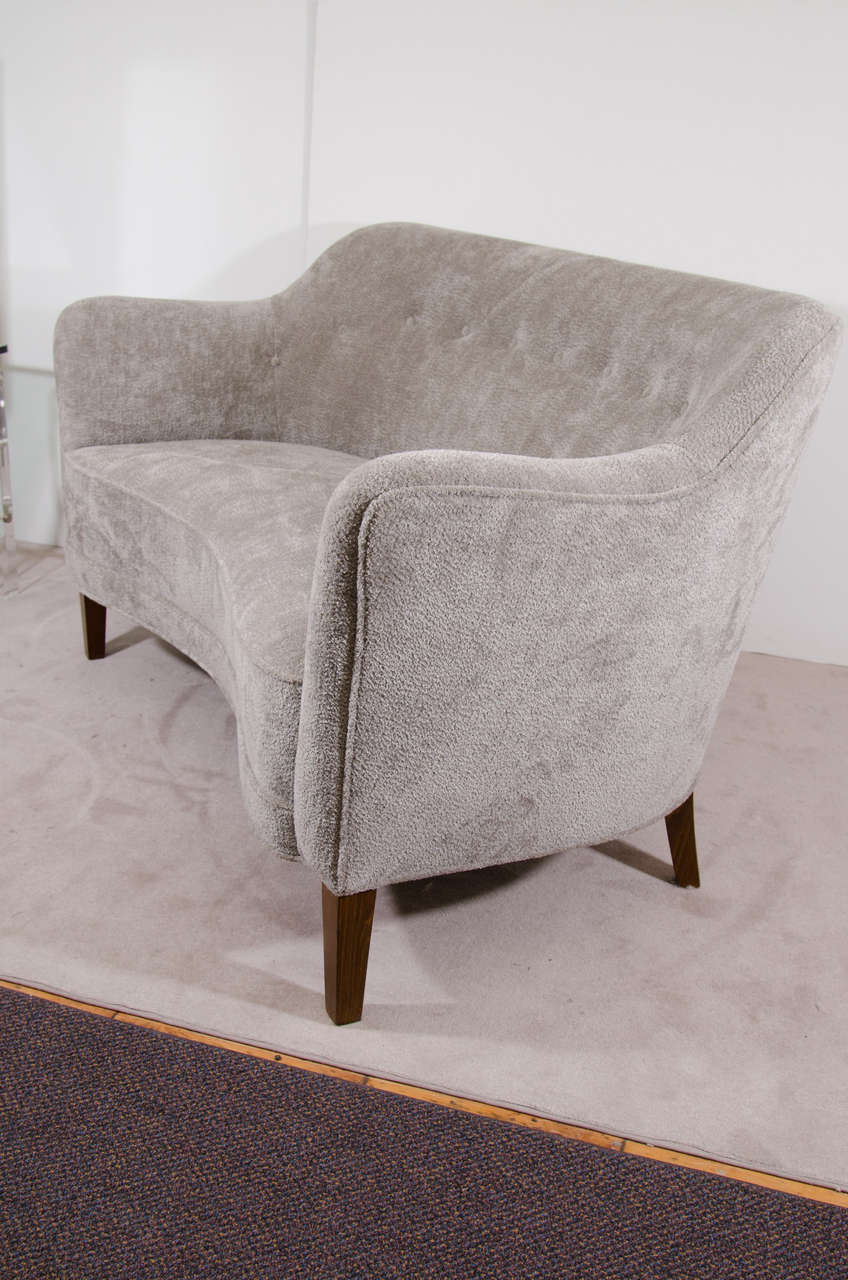 A Scandinavian Modern 1950s loveseat with tapering legs newly reupholstered in button tufted gray upholstery.

7993