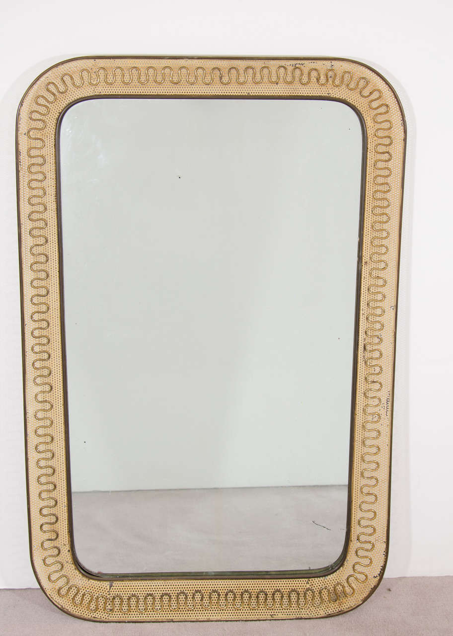 A vintage wall mirror with egg shell colored perforated metal frame and abstract design inspired by Gio Ponti.

Good vintage condition with age appropriate wear and patina. Some paint loss and cracking.