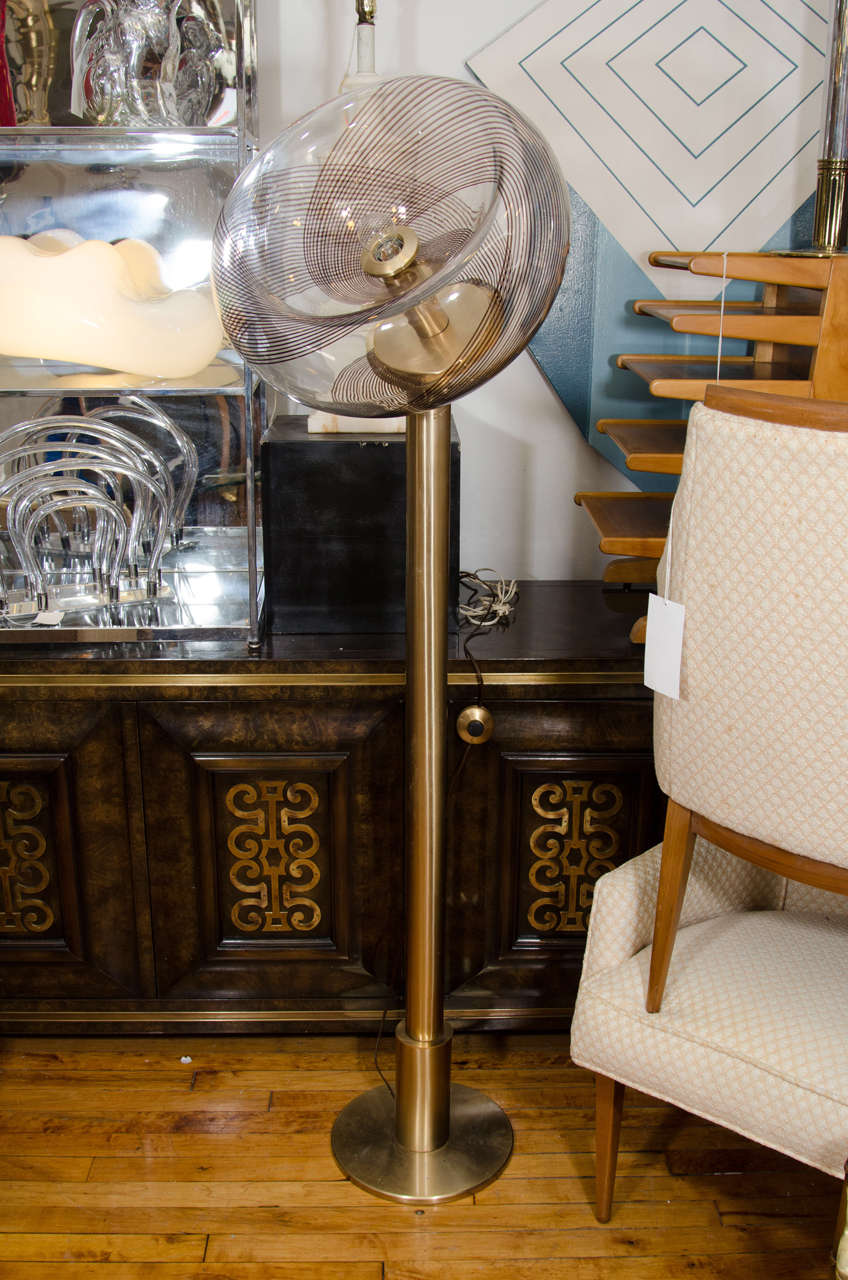 A vintage Murano swirl glass globe and brass floor lamp. There is a maker's mark in the glass globe. This lamp takes one Edison base bulb. Good vintage condition with age appropriate wear. Needs rewiring.