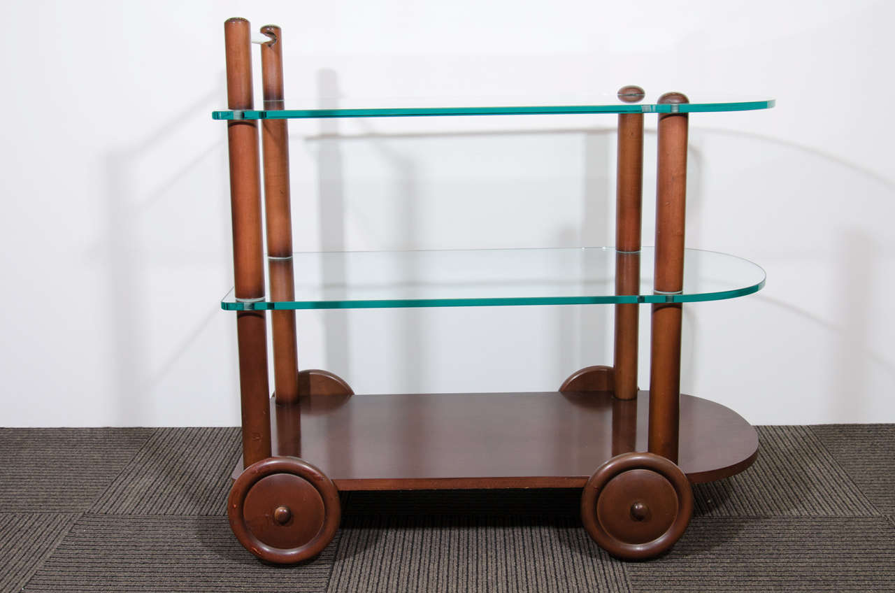 An Art Deco Gilbert Rohde bar cart, circa 1940s with all original glass including glass rod handle and wood finish.