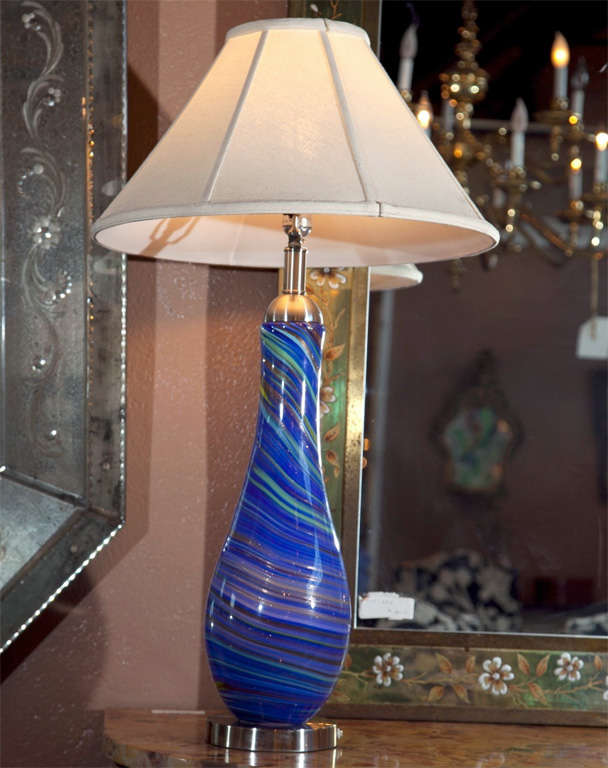 Pair of vintage Murano glass style table lamps. Each multi color one-piece glass lamps sitting on a chrome base with a matching chrome lidded top. The pair light in the interior as well as the top light bulb or both. The swirling painted center